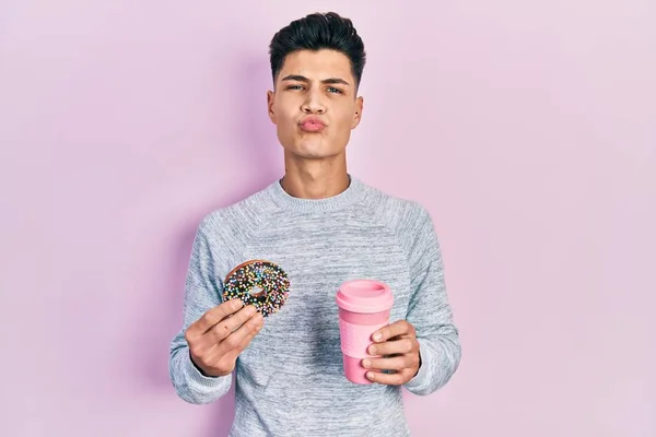 Jovem Hispânico Comendo Donuts Bebendo Café Olhando Para Câmera Soprando — Fotografia de Stock