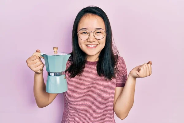 拿着意大利咖啡壶的中国女孩自豪地尖叫着 高举双臂庆祝胜利和成功 — 图库照片