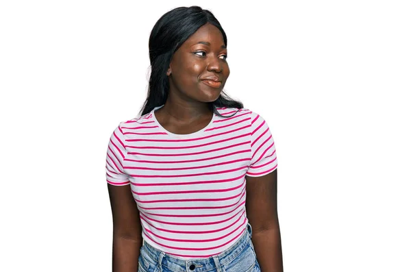 アフリカの若い女性は カジュアルな縞模様のTシャツを着て笑顔側を見て 離れて考えて見つめて — ストック写真