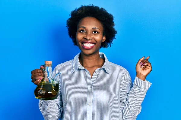 Joven Mujer Afroamericana Sosteniendo Aceite Oliva Puede Sonreír Feliz Señalando —  Fotos de Stock