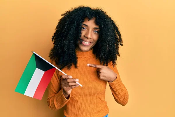 Африканская Американка Африканскими Волосами Держащая Флаг Кувейта Улыбается Показывая Пальцем — стоковое фото