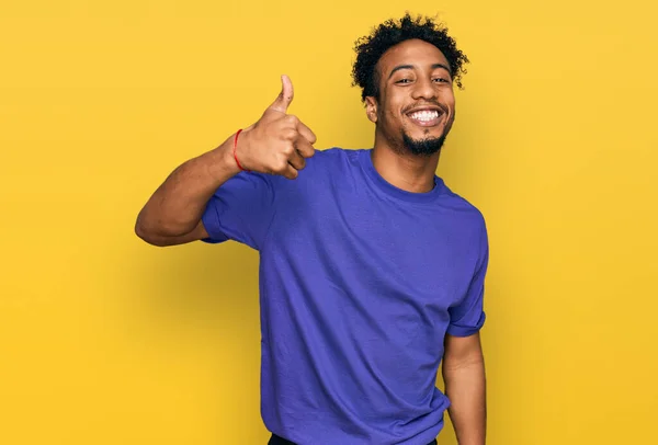 年轻的非洲裔美国人 留着胡子 穿着休闲的紫色T恤 手拿着快乐的大拇指做着快乐的手势 赞成的表情看着相机显示的成功 — 图库照片
