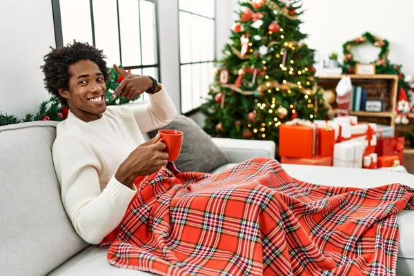 Joven Afroamericano Sentado Sofá Bebiendo Café Junto Árbol Navidad Sonriendo — Foto de Stock