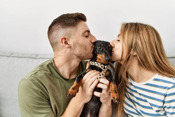 Jong Hispanic Paar Zoenen Hond Zitten Bank Thuis — Stockfoto