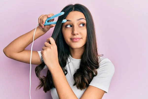 Young Hispanic Woman Holding Hair Straightener Smiling Looking Side Staring — Stock Photo, Image