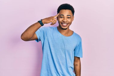 Genç Afro-Amerikan erkeği, günlük mavi tişörtler giyip tek parmağıyla gülümseyerek, harika bir fikir ya da düşünceyle, iyi bir hafızaya sahip. 