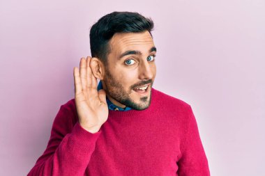 Gündelik kıyafetler giyen, ağzı kulaklarında gülümseyen genç İspanyol bir adam dedikoduları ve dedikoduları dinliyor. Sağırlık kavramı. 