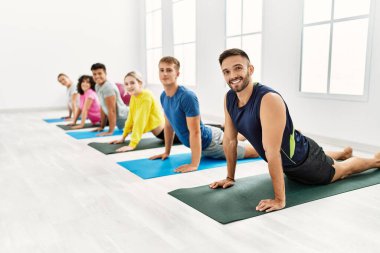 Spor merkezinde mutlu bir yoga eğitimi veren bir grup genç..