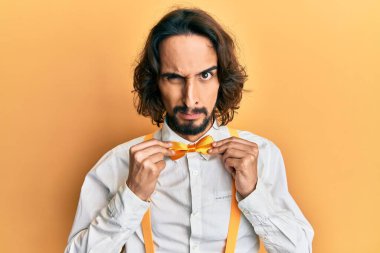 Hippi görünümlü genç İspanyol bir adam papyon takıyor kuşkucu ve gergin, sorun yüzünden suratını asıyor. negatif kişi. 