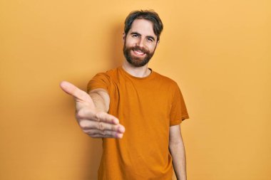 Sakallı, sıradan sarı tişörtlü, neşeli gülümseyen, yardım eli uzatan ve kabul gören beyaz bir adam.. 