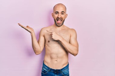 Genç kel adam kameraya hayret içinde ve gülümserken eliyle ve parmağıyla işaret ediyor.. 