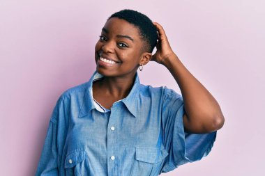 Gündelik giysiler giyen genç Afro-Amerikan kadın soru işaretlerini karıştırıyor ve merak ediyor. Şüpheyle kararsız, kafa kafaya düşünerek. Düşünceli kavram. 