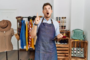 Perakende mağazasının müdürü olarak çalışan yakışıklı genç adam şaşkın ve şaşırmış bir şekilde yukarı bakıyor ve parmaklarıyla işaret ediyor ve kollarını kaldırıyor.. 