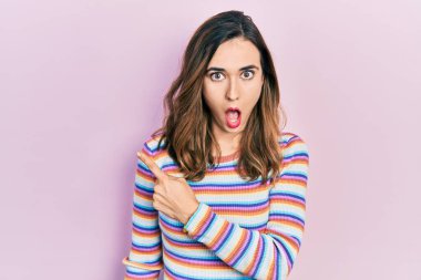 Gündelik kıyafetler giyen genç İspanyol kız parmaklarını yana doğru göstererek şaşırdı, ağzı açık hayret içinde kaldı.. 