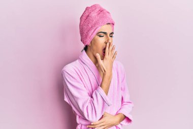 Kafasına duş havlusu ve bornoz takmış genç adam esnemekten sıkılmış, ağzı eliyle kapatmaktan sıkılmış. Huzursuz ve uykulu.. 