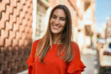 Genç İspanyol kadın gülümseyerek şehirde mutlu mesut dikiliyor..