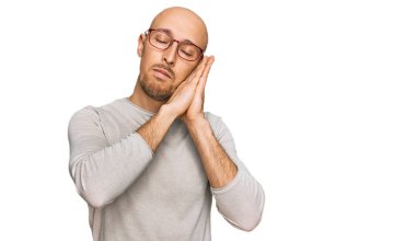 Kel, sakallı, günlük kıyafetler giymiş, gözlüklü, uykulu, yorgun, hayal kuran, elleriyle poz veren, gözleri kapalı bir adam.. 