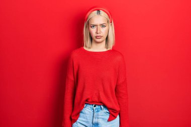 Güzel sarışın kadın, sıradan kırmızı süveter giyiyor şüpheci ve gergin, sorun yüzünden surat asıyor. negatif kişi. 