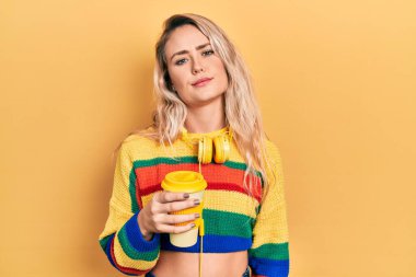 Güzel sarışın kadın bir fincan kahve içiyor kulaklık takıyor ve yüzünde ciddi bir ifadeyle rahatlıyor. Basit ve doğal bir şekilde kameraya bakıyorsun.. 