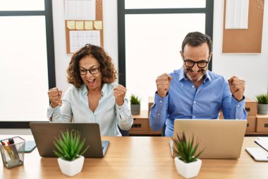 Ofiste yumrukları havada mutlu gülümseyen iki orta yaşlı iş adamı..