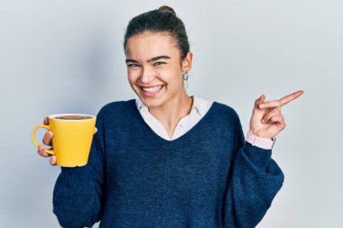Kafkasyalı genç kız elinde kahveyle mutlu bir şekilde gülümsüyor. 