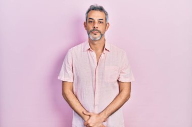 Gri saçlı, rahat gömlekli, yakışıklı, orta yaşlı bir adam. Yüzünde ciddi bir ifade var. Basit ve doğal bir şekilde kameraya bakıyorsun.. 
