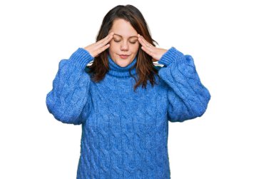 Genç ve cüsseli bir kadın stresten başı ağrıdığı için elleri başının üstünde gündelik kıyafetler giyiyor. migren ağrısı. 