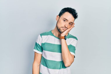 Günlük kıyafetler giyen genç İspanyol adam kollarını kavuşturarak depresyondan sıkılmış ve yorgun görünüyor.. 