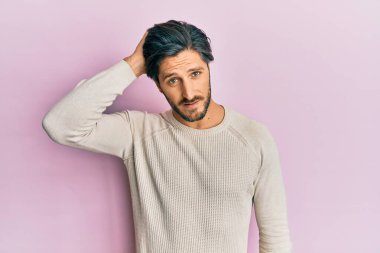 Kış süveteri giyen genç İspanyol adam soru sorup kafasını karıştırıyor. Şüpheyle kararsız, kafa kafaya düşünerek. Düşünceli kavram. 