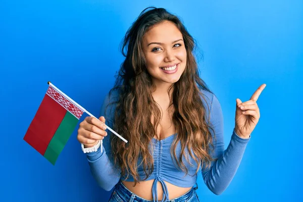 Mladá Hispánka Drží Běloruskou Vlajku Šťastně Usmívá Ukazuje Rukou Prstem — Stock fotografie