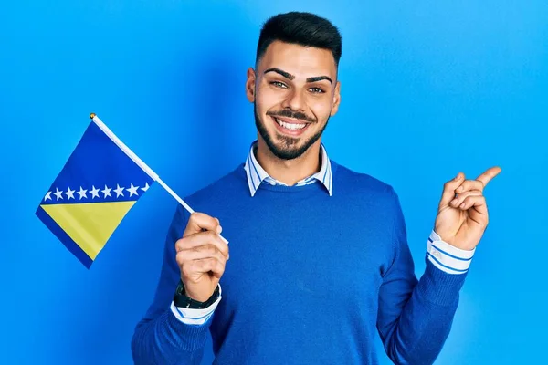 Joven Hispano Con Barba Sosteniendo Bandera Bosnia Herzegovina Sonriendo Feliz —  Fotos de Stock