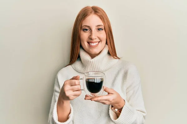 コーヒーを飲んでいる若いアイルランドの女性はポジティブで幸せな立ち位置を見て 歯を示す自信を持って笑顔で笑っています — ストック写真