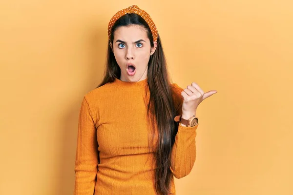 Young Brunette Teenager Wearing Casual Yellow Sweater Surprised Pointing Hand — Stock Photo, Image