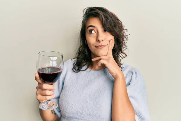 若いヒスパニック系の女性は 顎に手で質問について考える赤ワインの深刻な顔のガラスを飲んで 混乱のアイデアについて思慮深い — ストック写真