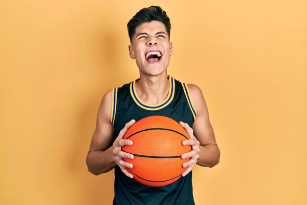 Молодой Латиноамериканец Держит Баскетбольный Мяч Злой Безумный Кричащий Расстроенный Разъяренный — стоковое фото