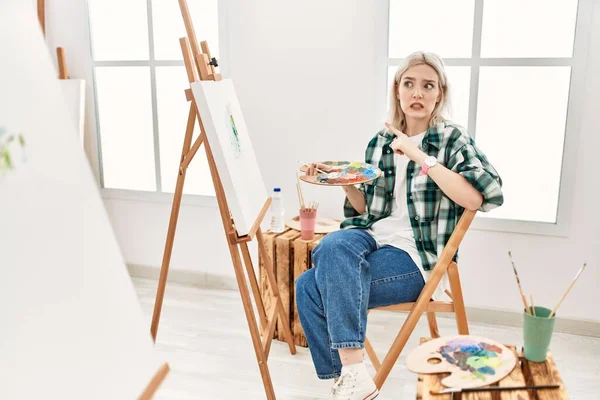 艺术工作室画布上的年轻艺术家妇女用食指 关心和惊讶的表情将焦虑和紧张抛在一边 — 图库照片