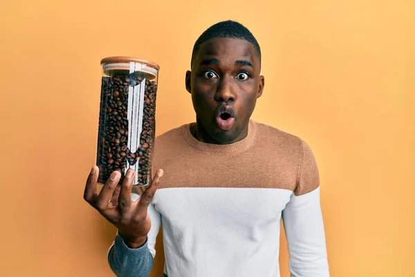 Joven Hombre Afroamericano Sosteniendo Frasco Con Granos Café Asustado Sorprendido — Foto de Stock