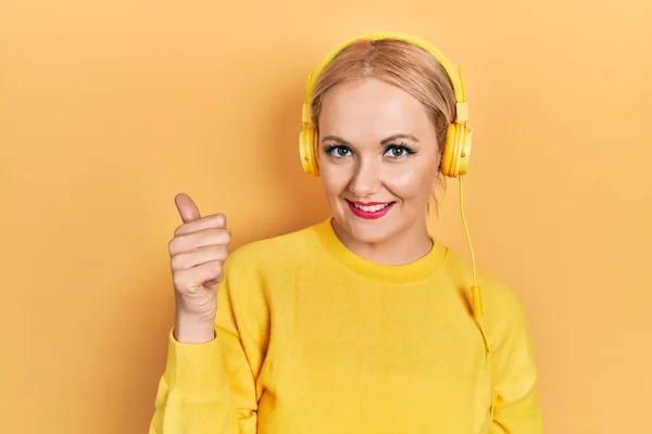 Genç Sarışın Kadın Müzik Dinliyor Kulaklık Takıyor Gülümsüyor Gülümsüyor Başparmağıyla — Stok fotoğraf