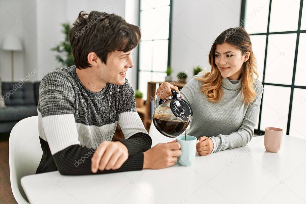 Young caucasian couple having breakfast pouring coffee on cup at home.