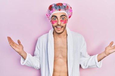 Bornoz ve duş başlığı takan genç İspanyol adam göz torbaları kullanıyor zaferi mutlu bir gülümsemeyle kutlayan bantlar ve ellerini kaldırarak kazanan ifade. 