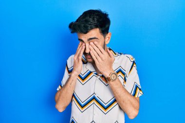 Günlük kıyafetler giyen genç İspanyol adam yorgunluk ve baş ağrısı için gözlerini ovuşturuyor, uykulu ve yorgun ifade. görme sorunu 