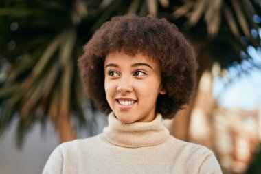 Genç İspanyol kız gülümseyerek şehirde mutlu mesut dikiliyor..