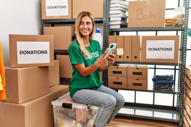 Hayır kurumunda çalışan beyaz bir gönüllü kız akıllı telefon kullanıyor..