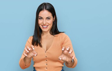 Genç İspanyol kadın gündelik kıyafetler giyip gülümsüyor. Pençe hareketlerini kedi gibi yapıyor. Agresif ve seksi bir ifade. 