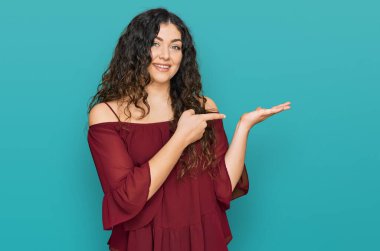 Gündelik kıyafetler giyen genç İspanyol kız kameraya hayret ediyor ve gülümsüyor.. 