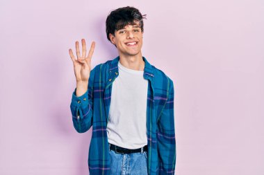 Yakışıklı hippi genç adam, günlük beyaz tişört ve klasik tişört giyip parmaklarını dört numarayı gösterirken kendine güvenen ve mutlu bir şekilde gülümsüyor.. 