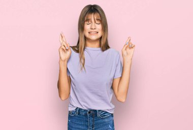 Gündelik giysiler giyen, umut ve gözlerin kapalı bir şekilde gülümseyerek el hareketi yapan beyaz bir genç kız. Şans ve batıl inançlar. 