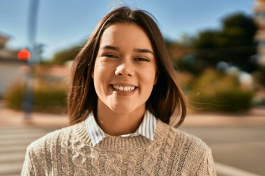 Genç İspanyol kız gülümseyerek şehirde mutlu mesut dikiliyor..