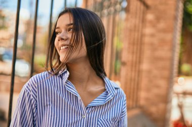 Genç İspanyol kız gülümseyerek şehirde mutlu mesut dikiliyor..