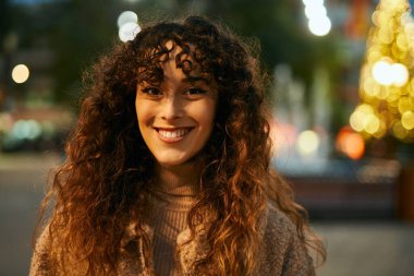 Genç İspanyol kadın gülümseyerek şehirde mutlu mesut dikiliyor.